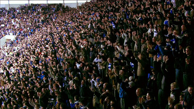 高角广角镜头拉近观众在足球比赛中欢呼在马德斯基体育场/雷丁，英国视频下载
