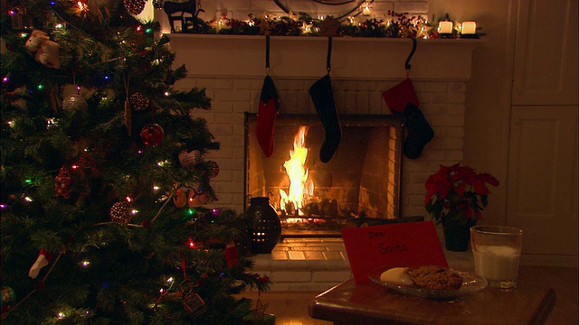 圣诞树旁的桌子上放着圣诞饼干和牛奶，背景是壁炉视频下载