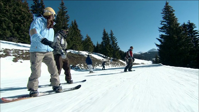 中镜头小车拍摄跟踪拍摄男子滑雪板下山与他人/莫辛，法国视频素材
