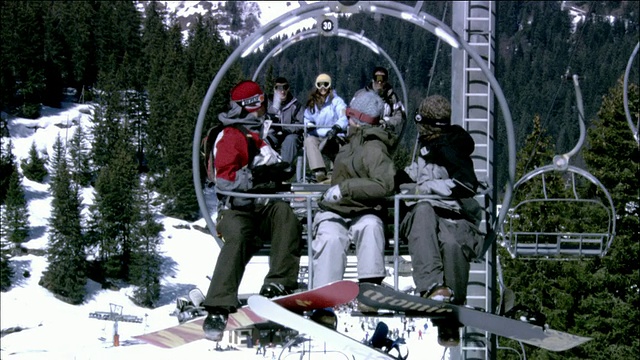中镜头滑雪板骑滑雪缆车和扔雪球其他椅子/ Morzine，法国视频素材