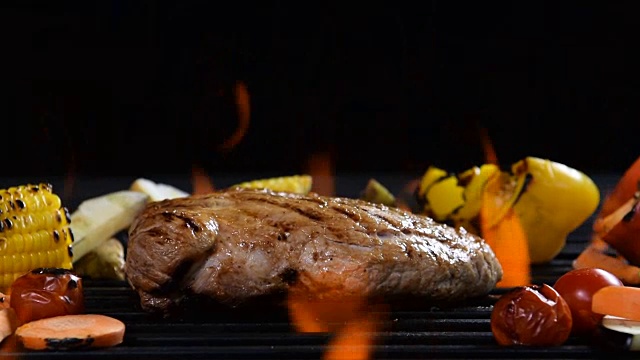 慢镜头-在燃烧的烤架上烤肉/牛排配蔬菜视频下载