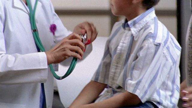 德克萨斯州埃尔帕索(El Paso)，一名中等镜头的医生在听小男孩的心跳/将听诊器放在男孩的前额视频素材