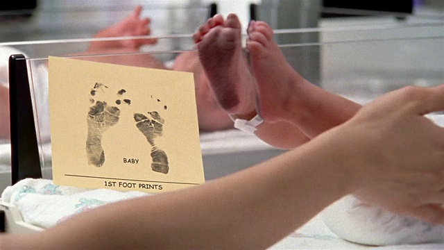 仔细观察宝宝的第一个脚印，放在宝宝/护士擦宝宝脚时沾有墨水的脚旁边视频素材