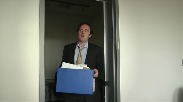 年轻的商人在被解雇后带着纸板箱离开办公室视频下载
