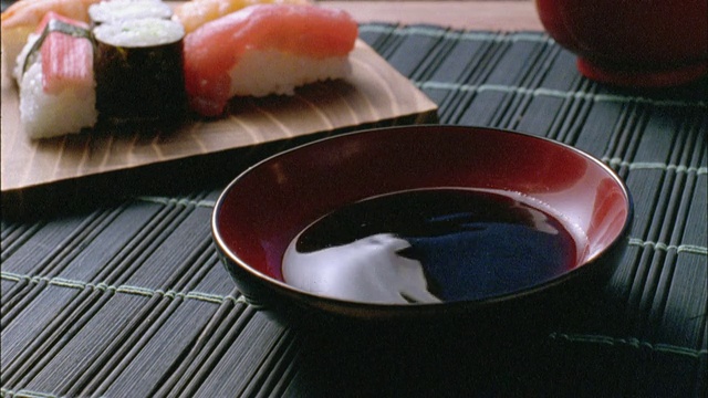 在酱油中蘸寿司卷的人，手的特写视频素材