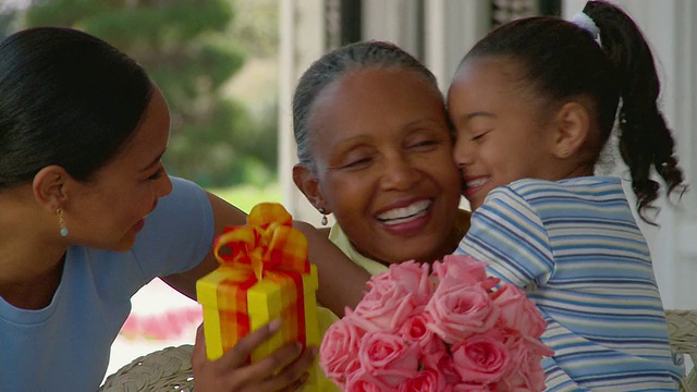 CU PAN女人和女孩拥抱亲吻她的祖母，同时拿着礼物和花束/里士满，弗吉尼亚州，美国视频下载