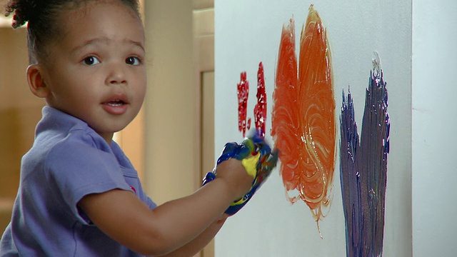 美国弗吉尼亚州里士满，一名用手蘸颜料和手指在墙上作画的女孩视频下载