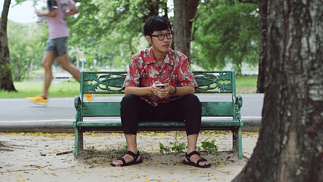 生活方式电影:年轻人在公园里使用手机。视频素材
