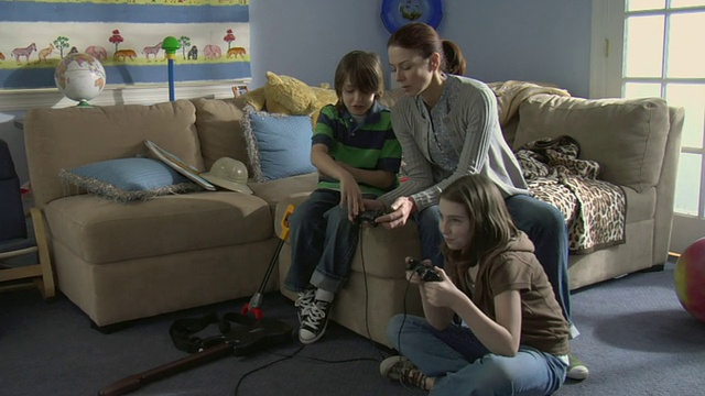 纽约怀特普莱恩斯，男孩向母亲展示如何玩电子游戏，女孩坐在地板上玩游戏视频素材