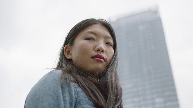 年轻女子站在摩天大楼旁边视频购买