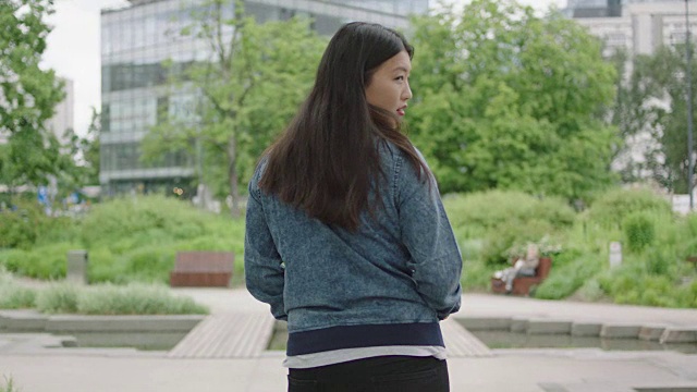 年轻女子走在摩天大楼旁边的背景视频素材
