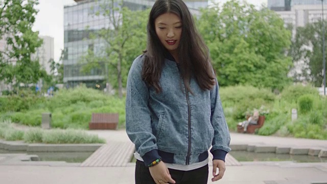 年轻女子摆姿势和微笑旁边的摩天大楼视频素材