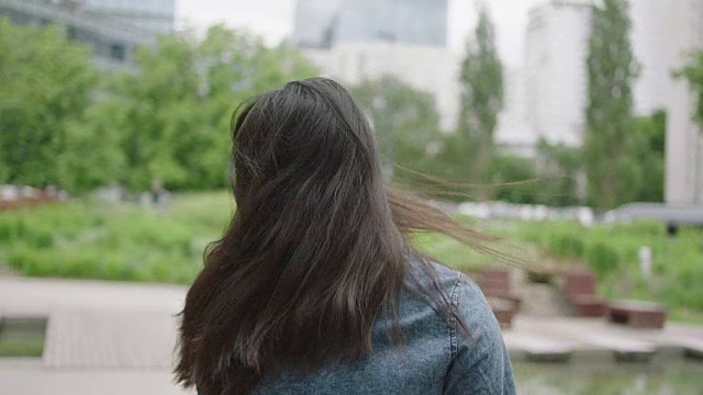 年轻女子转过身，微笑着靠近摩天大楼视频素材
