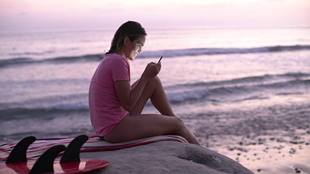 年轻女子坐在海滩边发短信视频下载