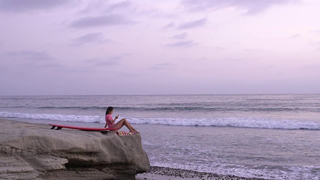冲浪后坐在海边的年轻女子视频下载