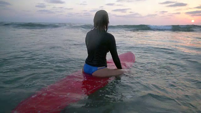 一名年轻女子坐在水中的冲浪板上视频下载