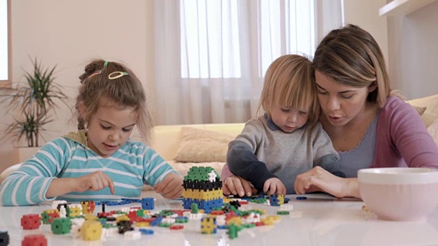 小孩子和他们的妈妈在客厅玩拼图游戏。视频素材