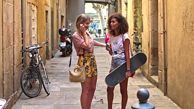 两个年轻女性朋友有乐趣分享音乐在街上视频素材