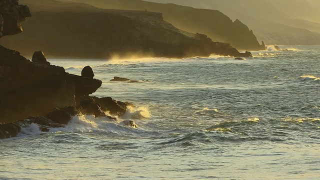 加那利群岛，雾霾日落时海浪撞击岩石海岸/富埃特文图拉视频下载