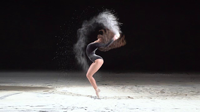 美丽的芭蕾舞者在一个旋转与粉雪在工作室。慢动作视频下载