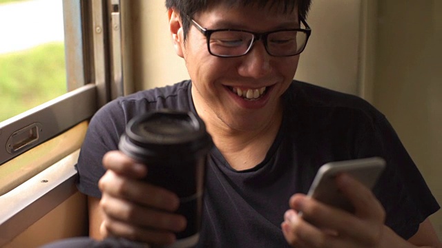戴眼镜的男人在火车上用智能手机喝咖啡视频素材