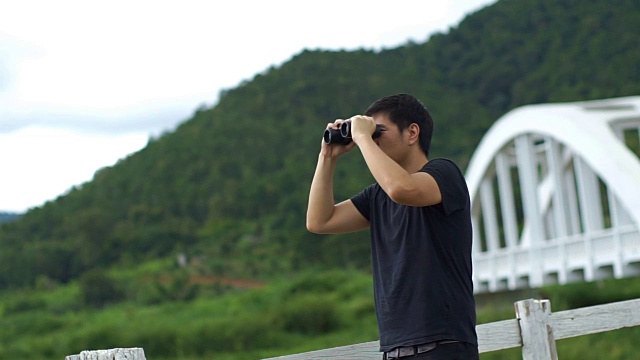 在大自然的群山背景中，人们用双筒望远镜看东西视频下载