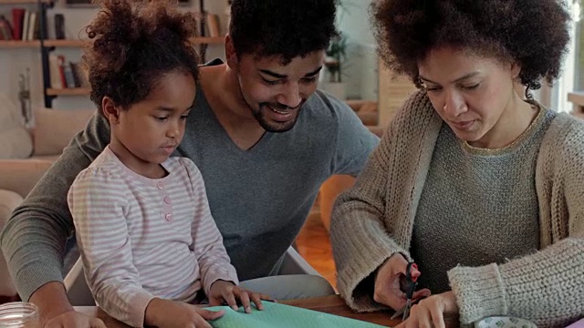 快乐的非裔美国家庭，在用纸和剪刀做一些有创意的东西时，玩得很开心。视频下载