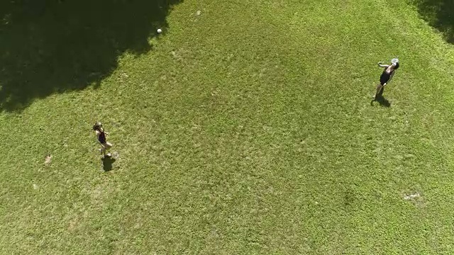 两个女人在草坪上打羽毛球。十几岁的女孩把帽子拿给她妈妈。俯视图直接上方，无人机视频视频素材