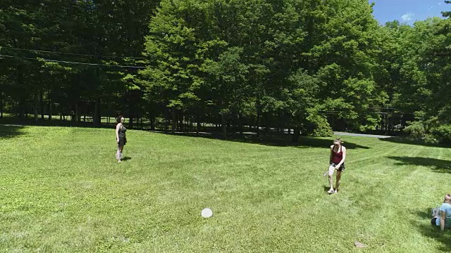 两个女人在草坪上打羽毛球，她们的女儿在看比赛。俯视图直接上方，无人机视频视频素材
