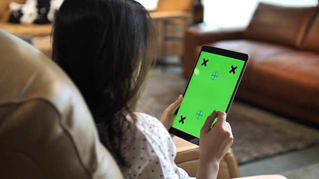 亚洲女性在家里使用绿色屏幕的数字平板电脑，色度键视频素材
