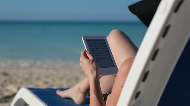 在海滩上阅读电子书的女人视频下载