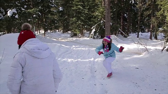 女孩和妈妈在冬天的公园里玩雪球视频素材