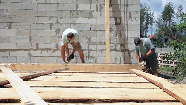 建筑工准备一根木梁来建造屋顶。视频素材