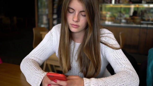 美丽的年轻女孩在咖啡馆发短信视频下载