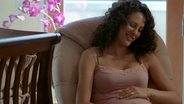 中镜头孕妇坐在椅子上，揉着肚子视频素材