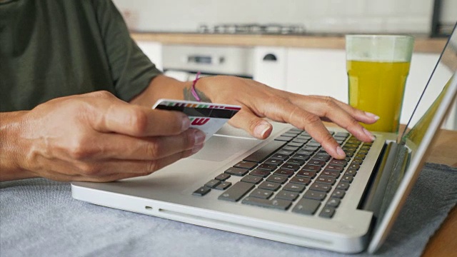 女人的手使用笔记本电脑和信用卡进行在线支付的特写。视频素材