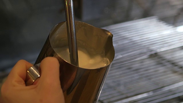 这是英国一家咖啡馆里牛奶被放在金属罐里蒸的特写镜头。视频素材