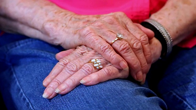 年长的成年女性手牵着手互相安慰。视频下载
