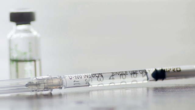 注射疫苗注射器与小瓶医疗近距离白色背景，摄影车拍摄从右到左视频素材