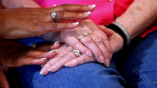 年长的成年女性手牵着手互相安慰。视频下载