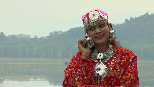 印度查谟和克什米尔达尔湖，穿着传统服装打电话的女士视频下载