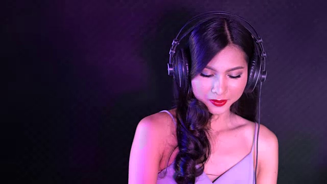亚洲女DJ在DJ的甲板上调整各种轨道控制视频下载