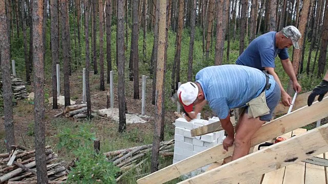 屋顶工人在屋顶上工作。建筑工人用锤子锤钉子。视频下载