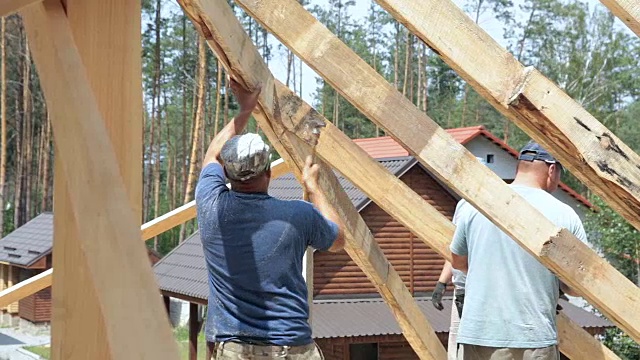 屋顶工人在屋顶上工作。建筑工人用锤子锤钉子。视频素材