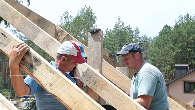 屋顶工人在屋顶上工作。建筑工人用锤子锤钉子。视频素材