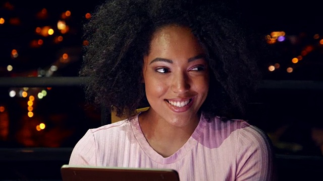 年轻女子在晚上使用平板电脑视频下载
