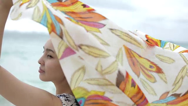 年轻快乐的女人在沙滩上伸出手，围巾，慢镜头视频下载