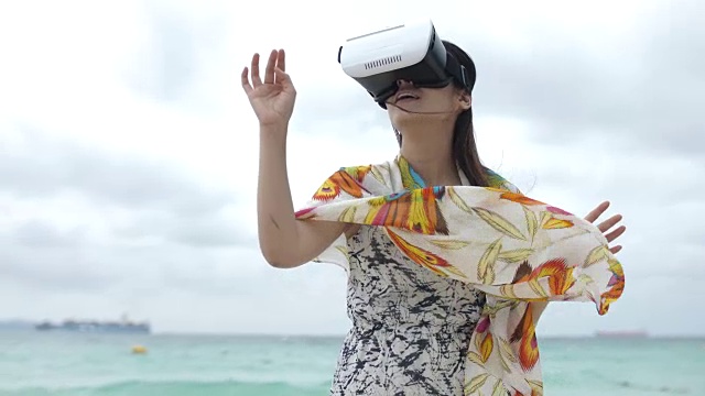 年轻的亚洲女人在海滩上用3d虚拟现实眼镜，慢镜头视频下载