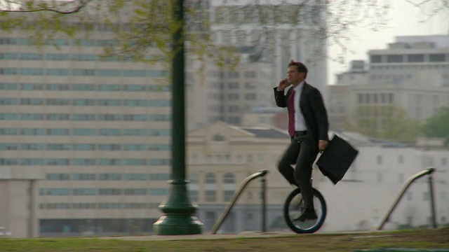 WS PAN商人骑着独轮车穿过公园，边骑边讲手机/弗吉尼亚州里士满视频下载