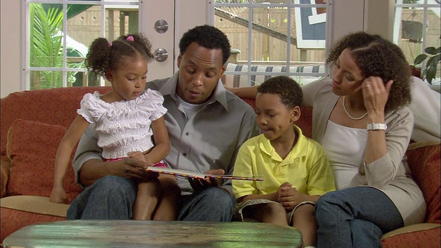 美国新泽西州韦斯特菲尔德，父亲给坐在沙发上的儿子(6-7岁)和女儿(4-5岁)读书视频下载